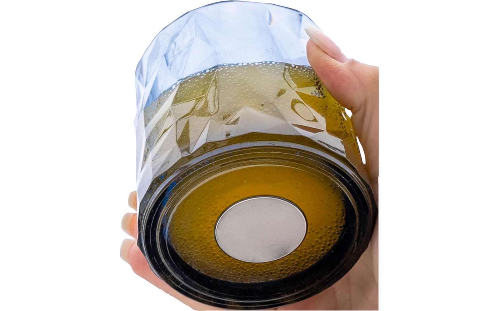 Hand holding an upside-down faceted drinking glass with a brown base and a white round mark on a white background