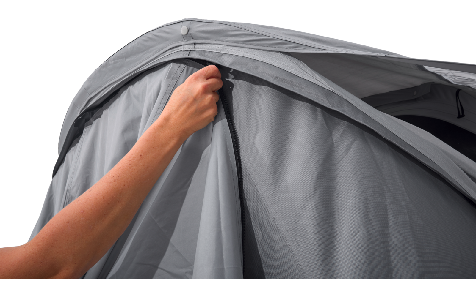 Hand zieht Reißverschluss an gebogenem grauen Stoff