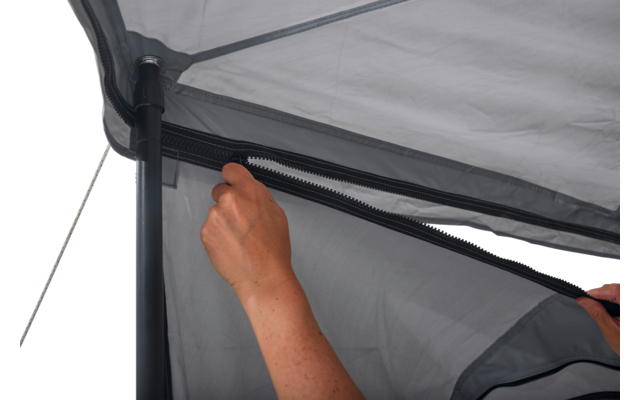 Zwei Hände halten einen Reißverschluss an grauem Zeltstoff neben einem schwarzen Gestänge