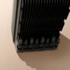 Schwarzes elektronisches Gerät mit mehreren Kühlrippen auf einer beige Oberfläche