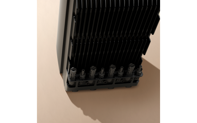 Schwarzes elektronisches Gerät mit mehreren Kühlrippen auf einer beige Oberfläche