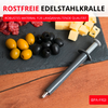 Outil métallique gris avec piston sur table en bois à côté d'une ardoise contenant des olives vertes et noires, des cubes de fromage et des tranches de salami ; texte rouge ROSTFREIE EDELSTAHLKRALLE et label rouge BPA-FREI