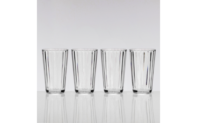 Quatre verres transparents côte à côte sur une surface blanche réfléchissante devant un fond gris clair