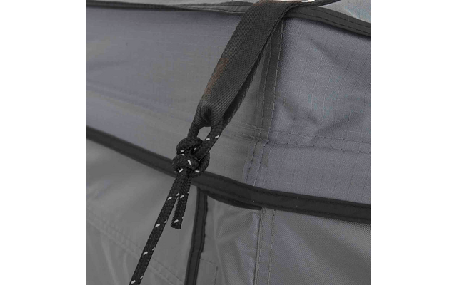 Nahaufnahme eines grauen Stoffs mit schwarzer Kordel, Knoten, zwei Kordelenden mit weißen Punkten und sichtbaren Nähten