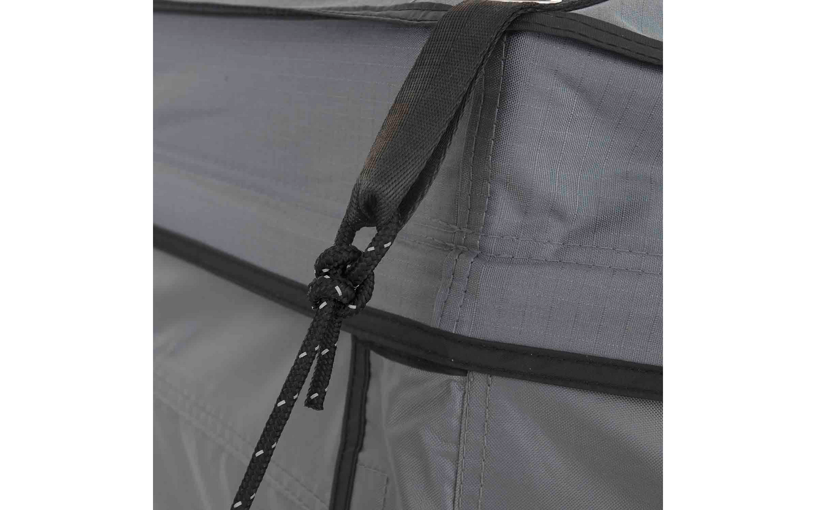 Nahaufnahme eines grauen Stoffs mit schwarzer Kordel, Knoten, zwei Kordelenden mit weißen Punkten und sichtbaren Nähten