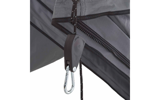 Graues Gewebe mit Reißverschluss, schwarzes Seil durch eine schwarze Kunststoffrolle, daran ein silberner Karabinerhaken; Metallstreben im Hintergrund