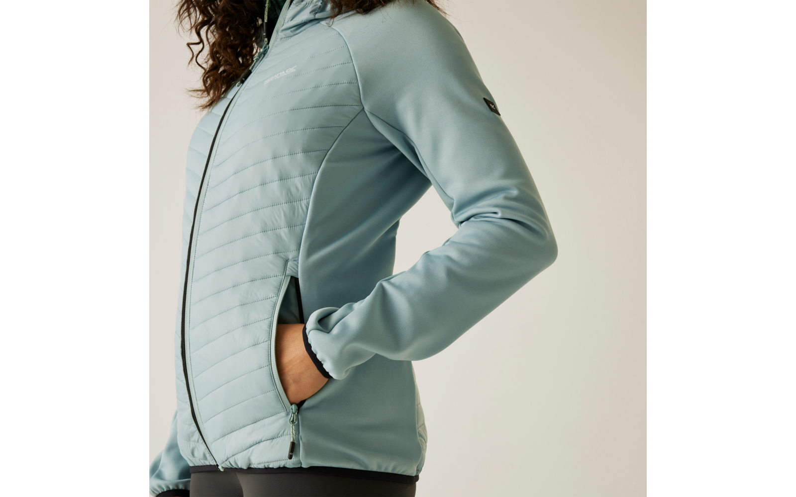 Personne portant une veste matelassée bleu clair, buste et bras visibles