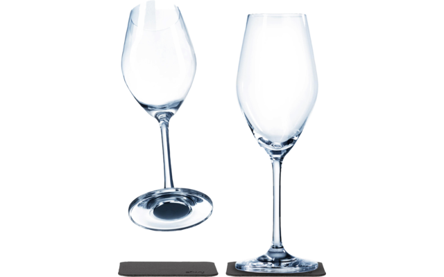 Two empty wine glasses, one standing on a black coaster, the other tilted on a black coaster