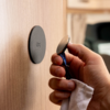 Hand holding a razor in front of a round holder on a wooden surface