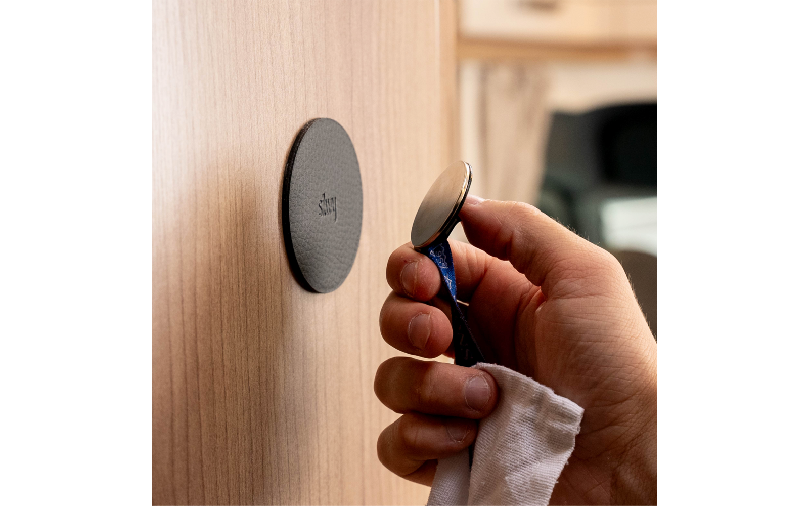 Hand holding a razor in front of a round holder on a wooden surface