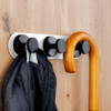 Black coat and light brown walking cane hanging on black hooks on a wooden rail