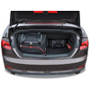 Offener Kofferraum eines grauen Autos mit einer schwarzen Reisetasche mit roten Akzenten, zwei kleinen schwarzen Taschen und einem roten Objekt rechts