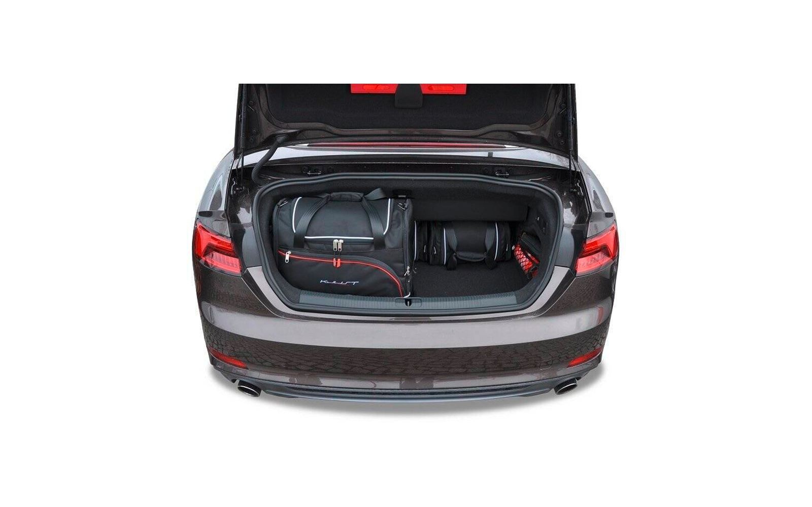 Offener Kofferraum eines grauen Autos mit einer schwarzen Reisetasche mit roten Akzenten, zwei kleinen schwarzen Taschen und einem roten Objekt rechts