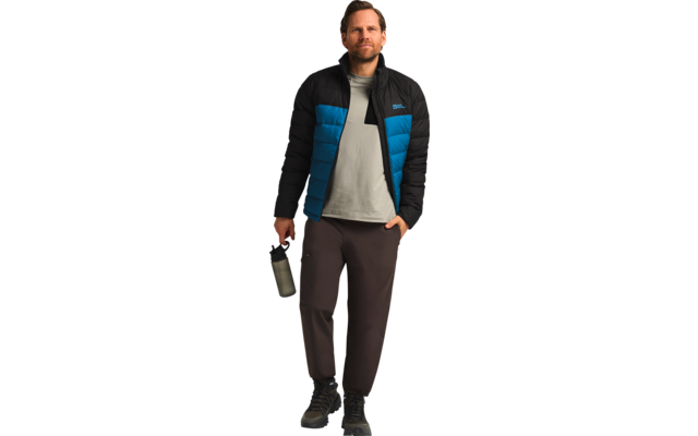 Mann mit Jacke, hellem T-Shirt und dunkler Hose stehend