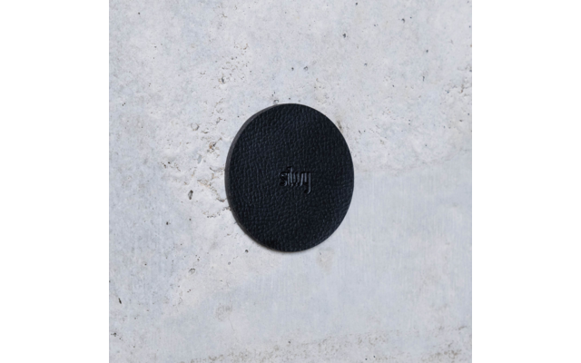 Black round sticker with the word 'stay' on a light, textured background