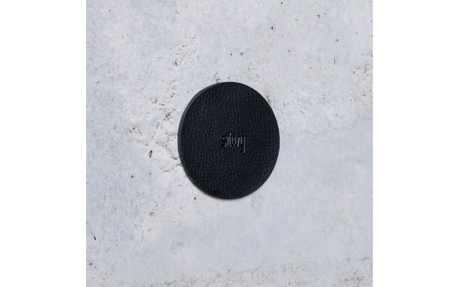 Black round sticker with the word 'stay' on a light, textured background