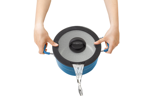 Wasser wird aus einem Topf mit Deckel in eine Spüle gegossen, zwei Hände halten den Topf