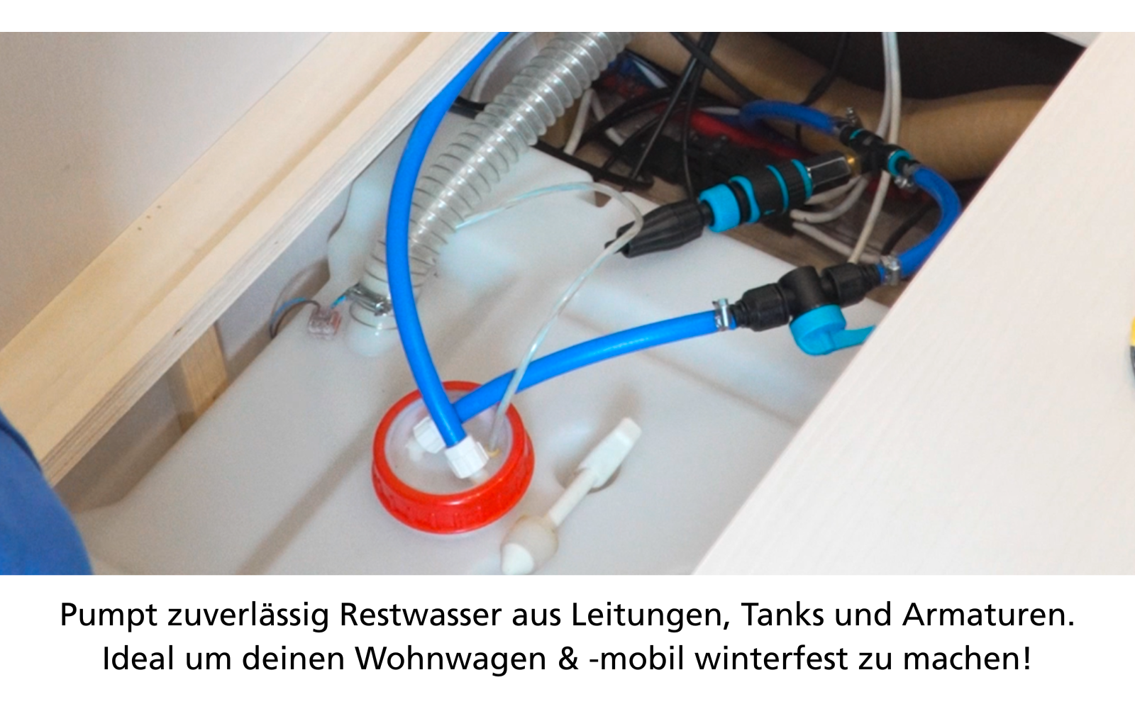 Scompartimento in legno aperto con un contenitore di plastica bianco con tappo a vite rosso, un tubo blu e un tubo bianco inseriti; tubo corrugato grigio, pinza con impugnature nero-blu, raccordi metallici e piccoli pezzi