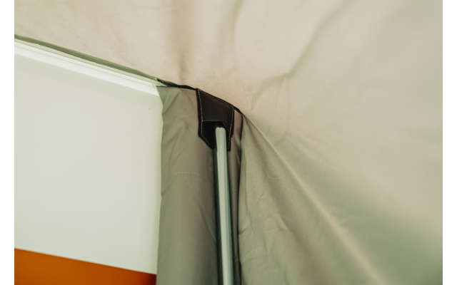 Binnenaanzicht van lichtgekleurde stof met een verticale zilverkleurige metalen staaf en zwarte kunststofverbinder; stofplooien rechts, een oranje-witte streep links