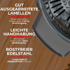 Gros plan d'une pièce ronde en acier inoxydable perforée sur une surface en bois, avec du texte allemand en blanc et rouge superposé