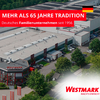 Vue aérienne d'un site d'entreprise avec toits plats, panneaux solaires, camions garés et arbres ; bande rouge en haut à gauche avec le texte MEHR ALS 65 JAHRE TRADITION et Deutsches Familienunternehmen seit 1956 et drapeau allemand ; en bas à droite zone blanche avec le logo Westmark et le slogan Mach's einfach !