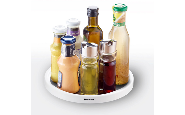 Seven bottles and dispensers with various light and dark liquids on a round white tray