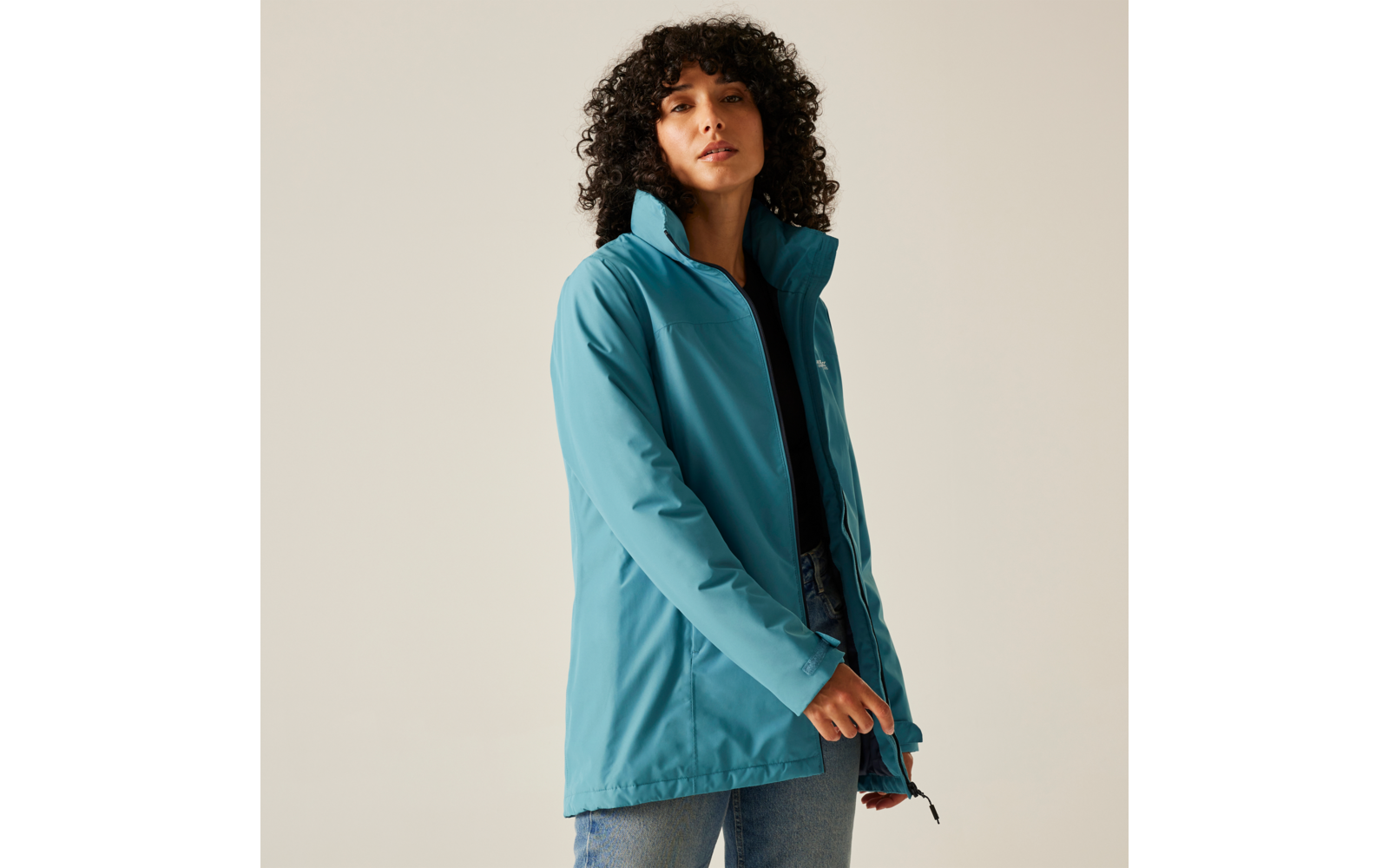 Femme aux cheveux bouclés portant une veste bleue regardant devant