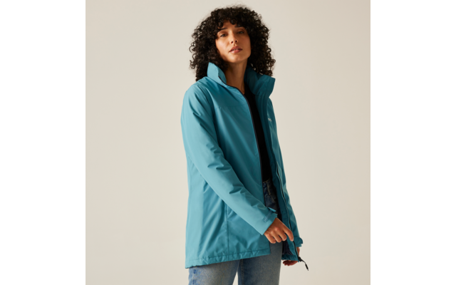 Femme aux cheveux bouclés portant une veste bleue regardant devant