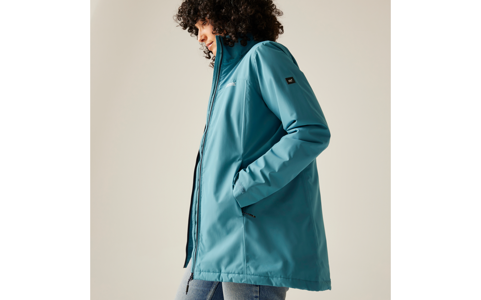 Femme aux cheveux bouclés portant une veste bleue regardant de côté