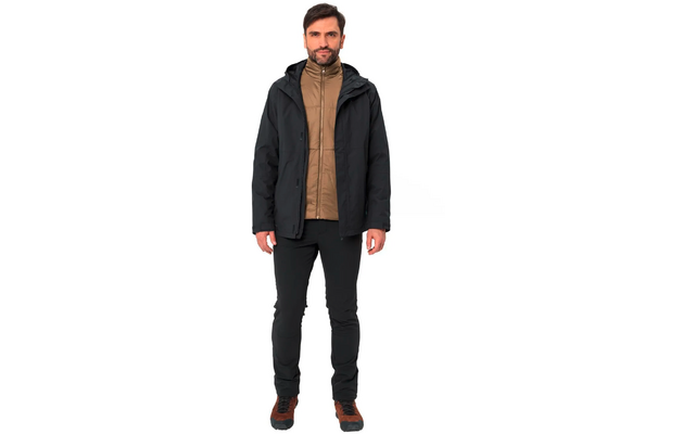 Mann mit dunklem Mantel, braunem Pullover und schwarzen Hosen steht frontal