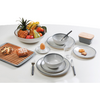 Weißer Tisch mit grauen Tellern und Schüsseln, Löffel in einer Schüssel, Glas, Messer und Gabel, Eierbecher mit Ei, große Obstschale mit Ananas, Bananen, Äpfeln und Birnen, Holzbrett mit Brötchen und Laugengebäck, kleine Platte mit Keksen, rechteckig