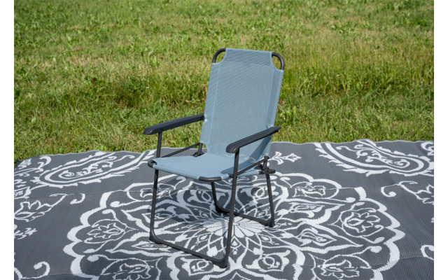 Lichtblauwe klapstoel met metalen frame op een deken met zwart-wit patroon op gras