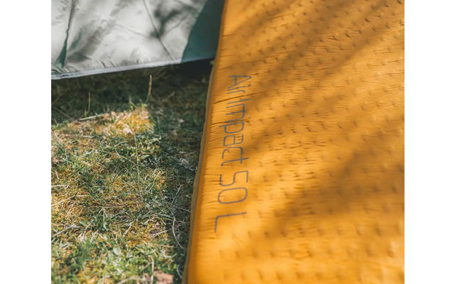 Nahaufnahme einer gelben Matte auf Gras mit der Aufschrift ‚JOGA‘