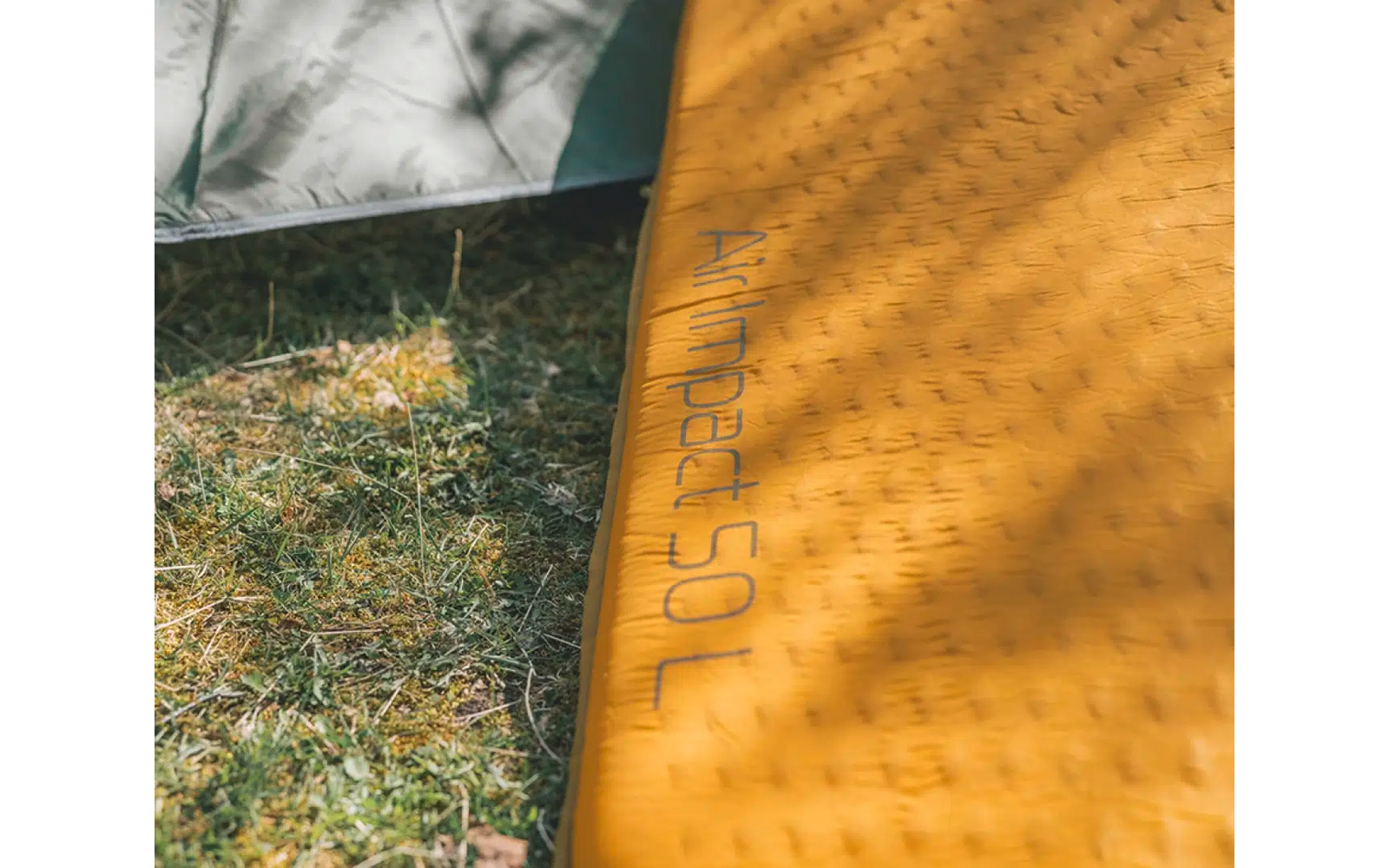 Nahaufnahme einer gelben Matte auf Gras mit der Aufschrift ‚JOGA‘