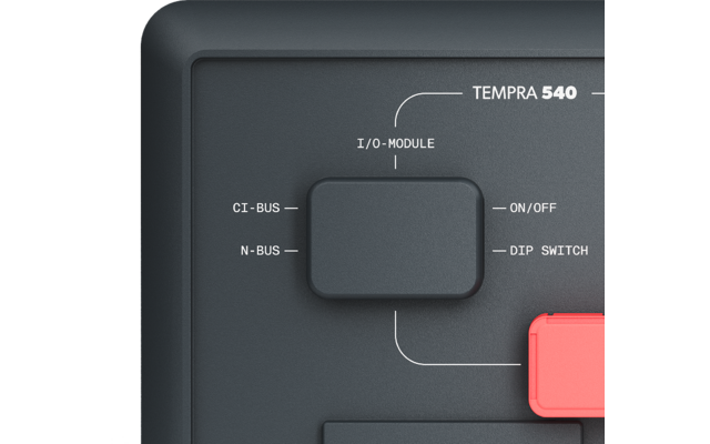 Gros plan d'une face d'appareil gris foncé avec l'inscription TEMPRA 540, un module I/O carré gris foncé, les étiquettes CI-BUS, N-BUS, ON/OFF, DIP SWITCH et un bouton rectangulaire rouge à droite