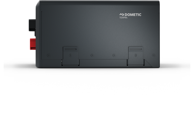 Boîtier rectangulaire gris foncé avec le logo « Dometic » en haut, deux bornes de connexion à gauche (rouge et noir) et deux trappes sur la partie inférieure avant