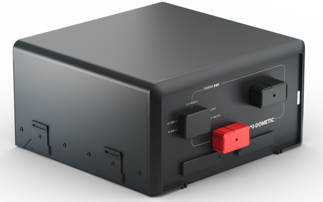 Dunkelgraues rechteckiges elektronisches Gerät mit abgerundeten Kanten; vorne zwei rechteckige Anschlussstecker, einer rot und einer schwarz; auf hellgrauem Untergrund