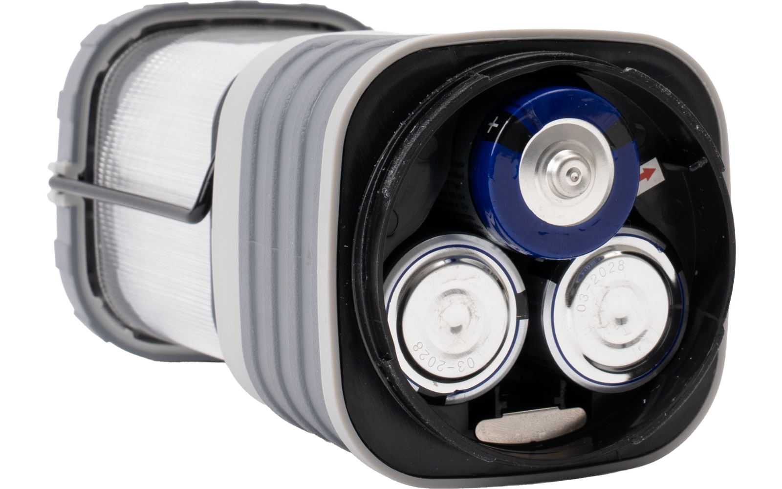 Drie cilindrische batterijen (één met blauwe bovenkant, twee met zilverkleurige bovenkanten) in een zwarte kunststof behuizing met grijze rand; daarnaast een witte, doorschijnende lampenkap zichtbaar