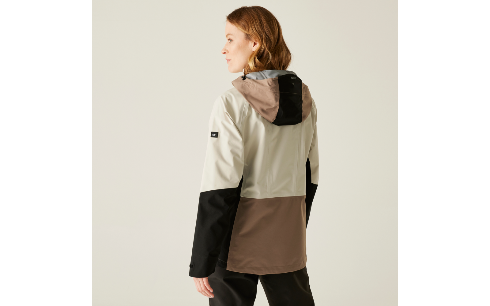 Frau zeigt Rückansicht, trägt eine dreifarbige Jacke in Beige, Schwarz und Braun