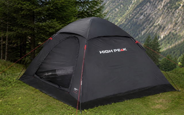 Black dome tent with 'HIGH PEAK' logo, partially open mesh door, red guy lines, on grass in front of conifer trees and a mountain slope