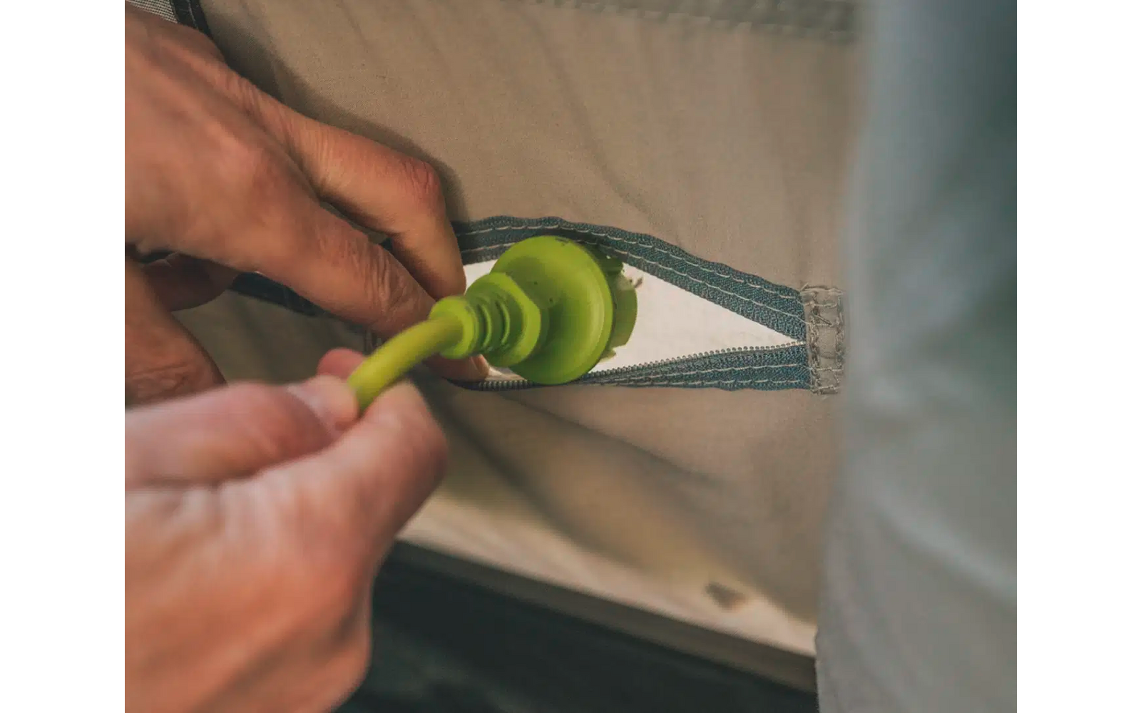 Hände einer Person, die grünes Gemüse mit einem Messer auf einem Holzbrett schneiden