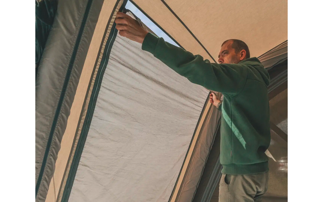 Mann zieht Vorhang an großem Fenster auf
