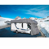 Weißes Wohnmobil mit grauer Abdeckung an der Front, auf einer schneebedeckten Bergstraße mit Schneehaufen und blauem Himmel