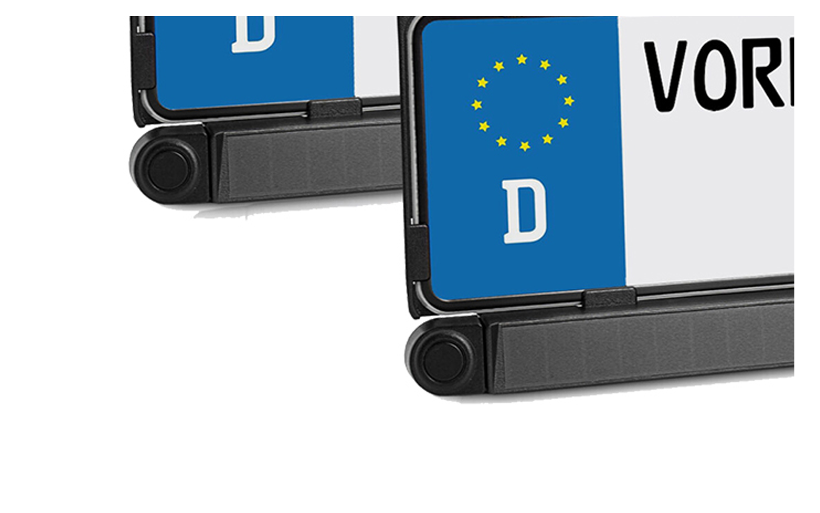 Gros plan de deux plaques d'immatriculation, bande bleue avec étoiles jaunes et lettre blanche 'D', lettres noires partiellement visibles 'VOR' sur fond blanc, support en plastique noir en bas