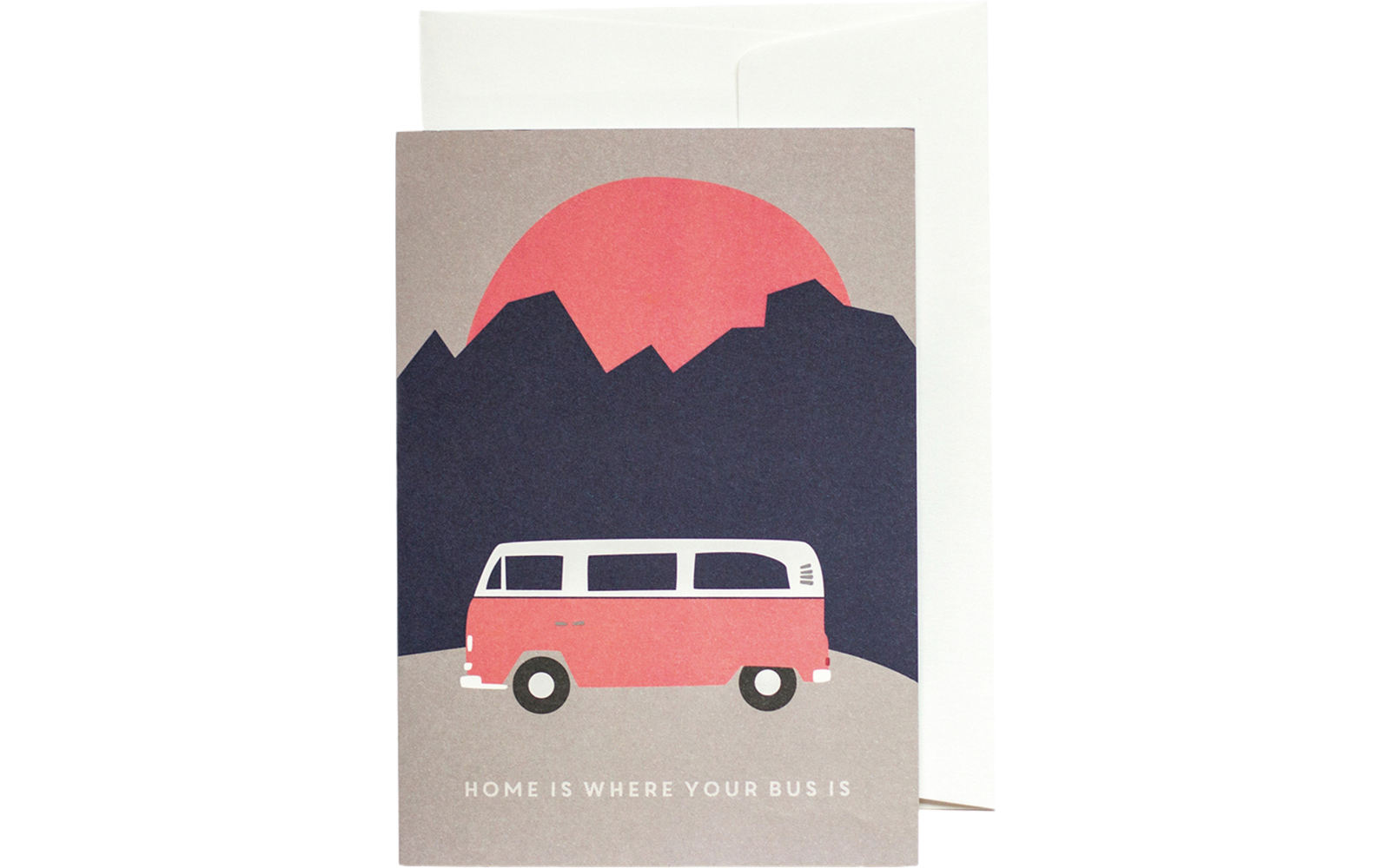 Karte vor weißem Umschlag; auf der Vorderseite ein roter Kreis hinter dunklen Bergsilhouetten, ein rosa Kleinbus mit weißem Dach in Seitenansicht und unten der Schriftzug 'HOME IS WHERE YOUR BUS IS'