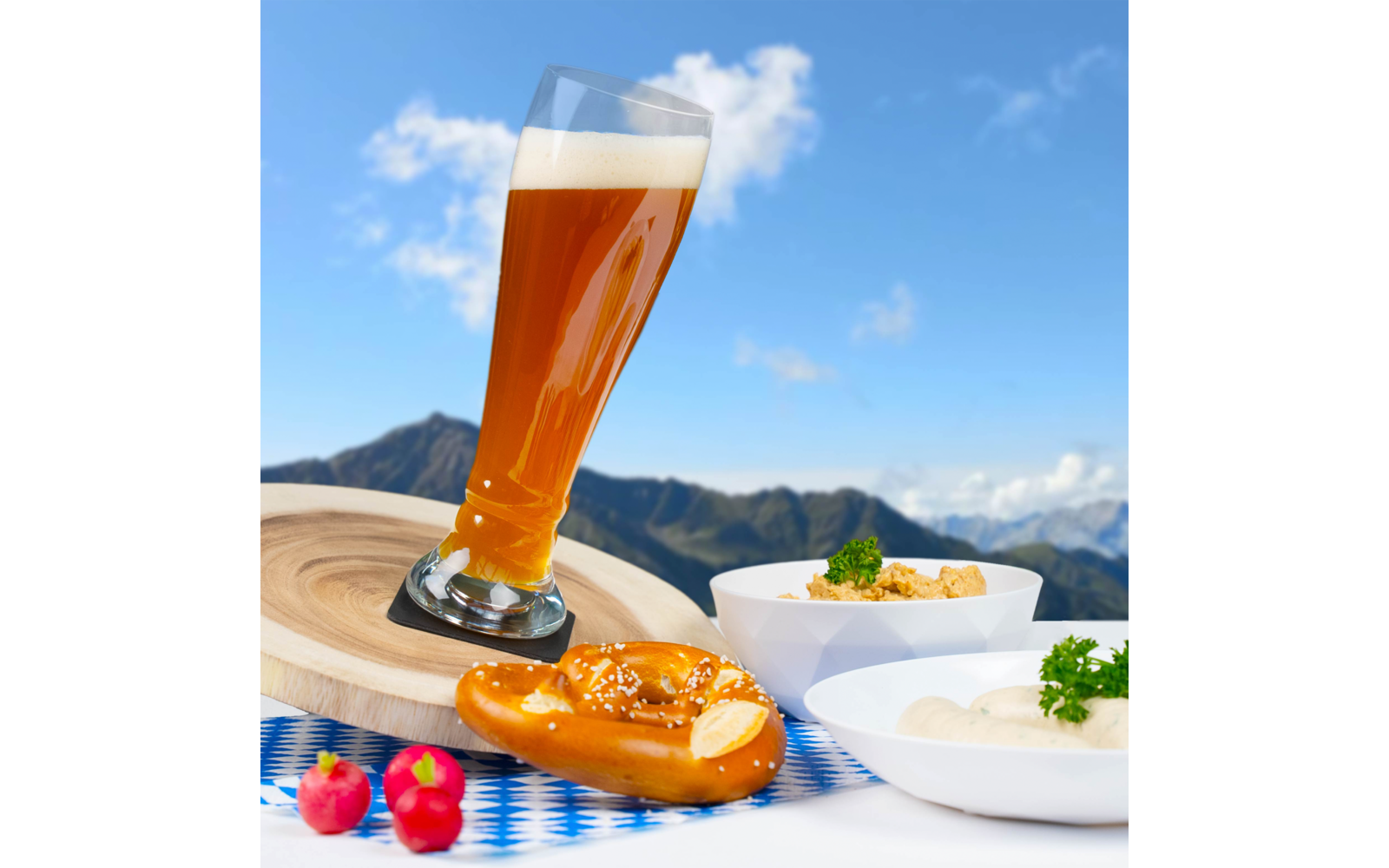 Bierglas, Brezel, zwei kleine Schalen mit Essen und drei Radieschen vor Bergpanorama