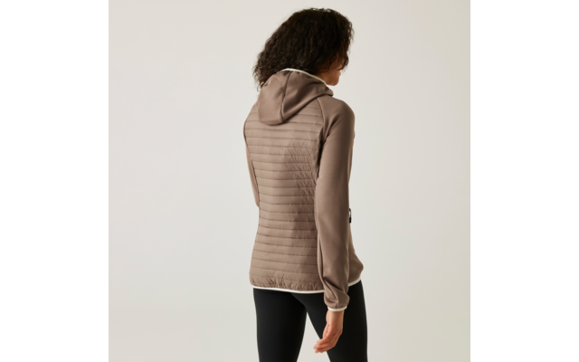 Femme aux cheveux bouclés portant un sweat à capuche beige et un pantalon noir, photographiée de dos