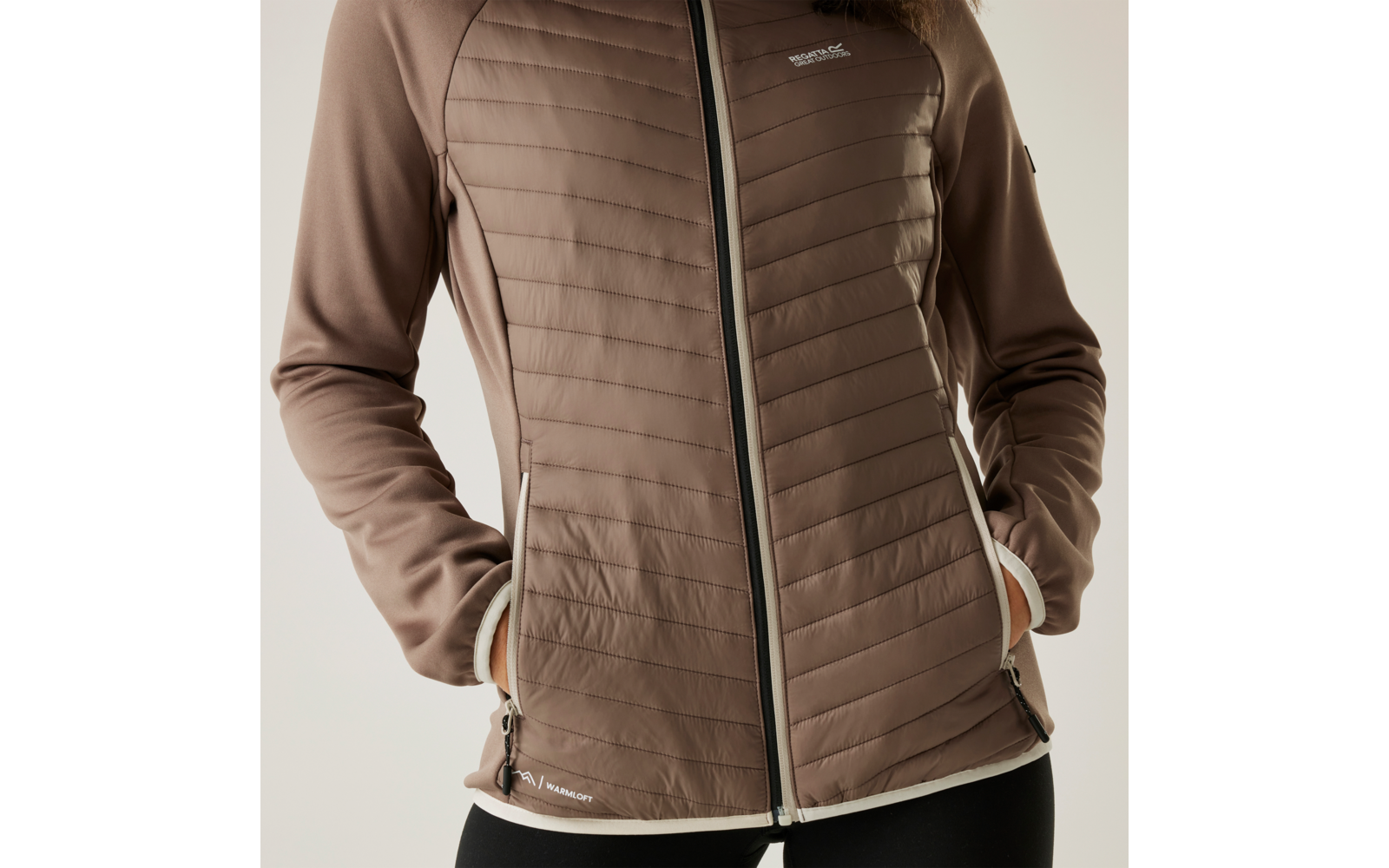 Personne portant une veste matelassée marron avec fermeture éclair et un pantalon noir
