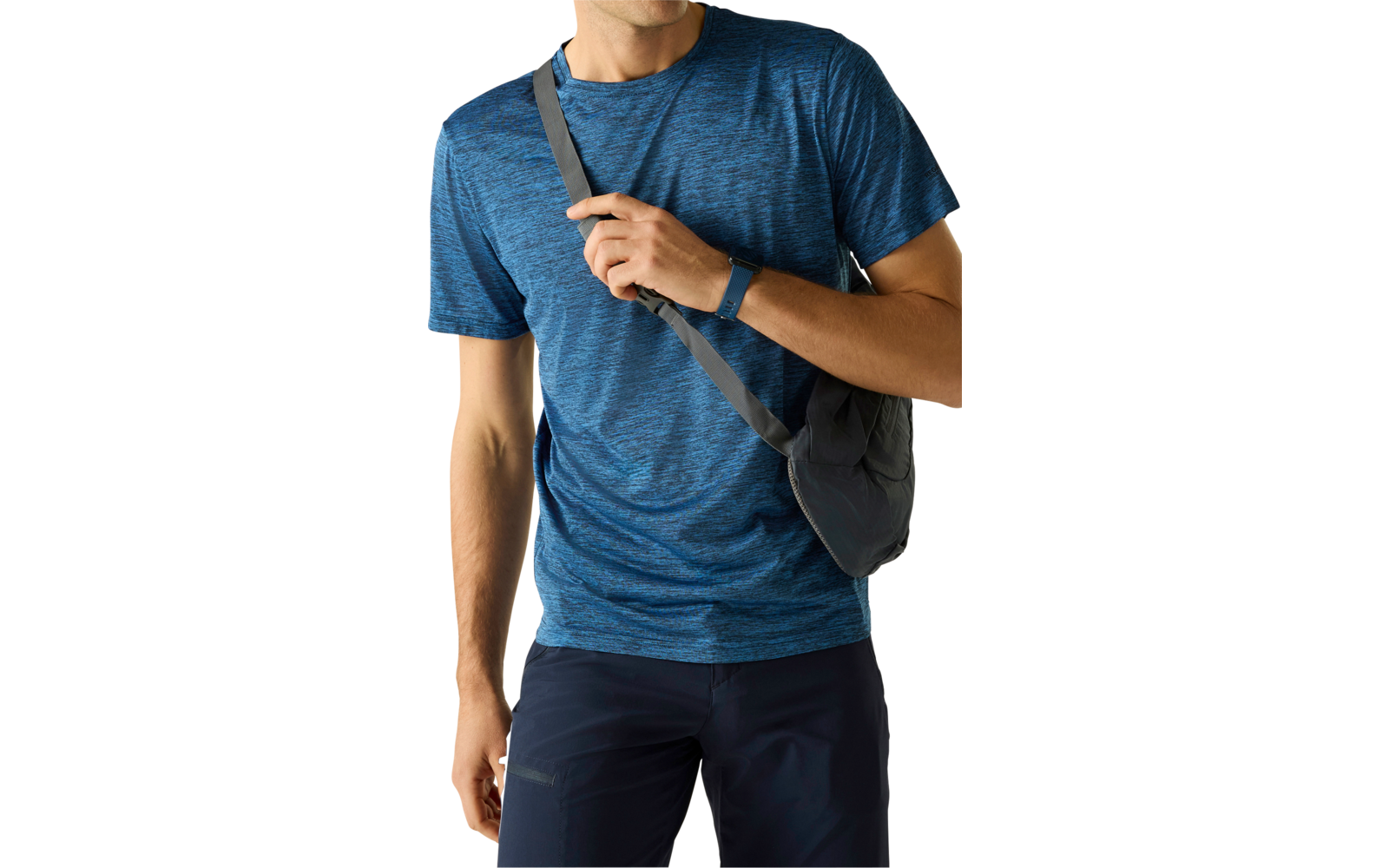 Mann in blauem T-Shirt und dunkler Hose, trägt eine Umhängetasche quer über der Brust, blickt nach links, linke Hand hält den Taschenriemen, heller einfarbiger Hintergrund