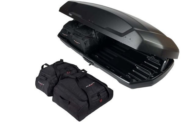Offener schwarzer Dachkoffer und drei schwarze Reisetaschen auf weißem Hintergrund